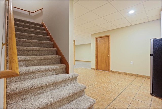 staircase featuring tile patterned flooring, baseboards, and a drop ceiling