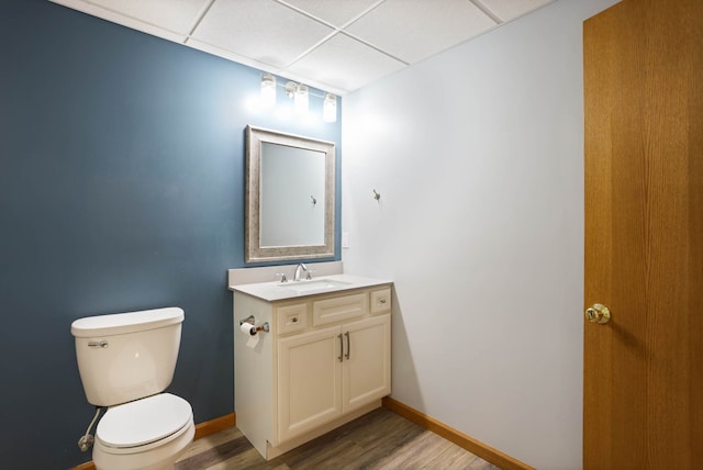 bathroom featuring a paneled ceiling, baseboards, toilet, and wood finished floors