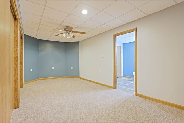 carpeted spare room featuring a ceiling fan, a paneled ceiling, and baseboards