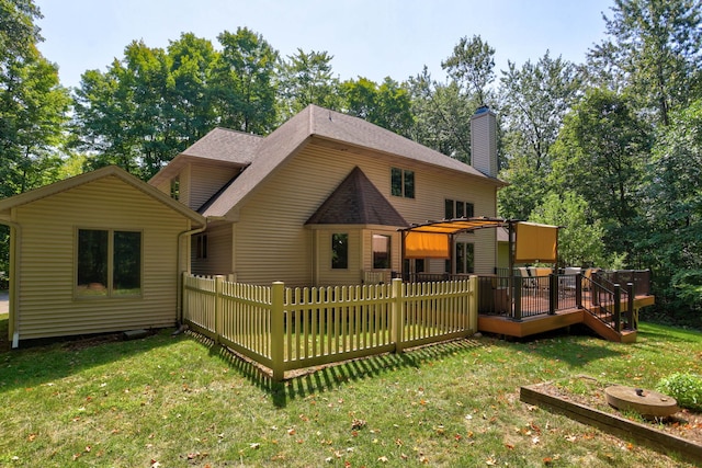 back of house with roof with shingles, a lawn, a chimney, and a wooden deck