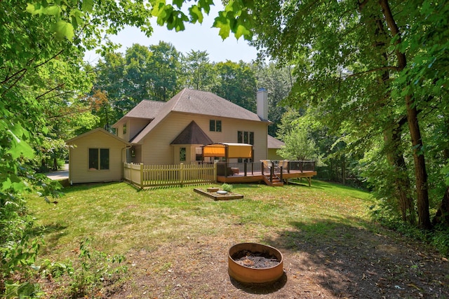 back of property with an outdoor fire pit, a wooden deck, a chimney, fence, and a yard