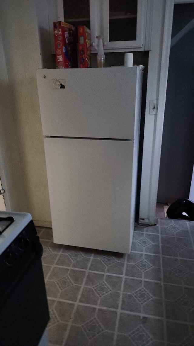 kitchen featuring tile patterned floors, black electric range oven, and white fridge