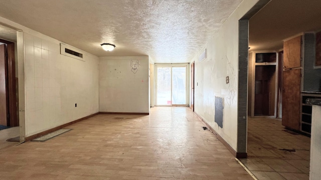 unfurnished room with a textured ceiling and light hardwood / wood-style floors