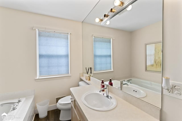 bathroom with a relaxing tiled tub, vanity, and a wealth of natural light