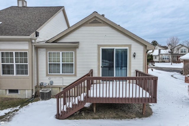 snow covered back of property with a wooden deck and central AC