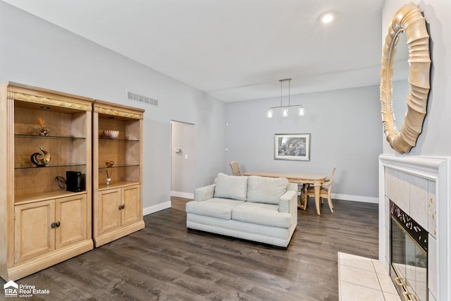 living room featuring dark wood-type flooring, a chandelier, and a tile fireplace