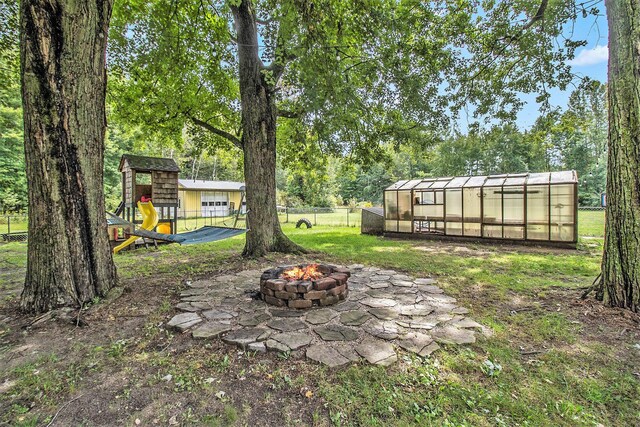 1722 N Benson Rd, Fountain, MI 49410 - view of yard with an exterior structure, an outdoor fire pit, an outdoor structure, and view of wooded area