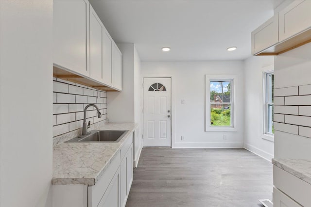 kitchen with light wood-type flooring, tasteful backsplash, white cabinetry, and sink