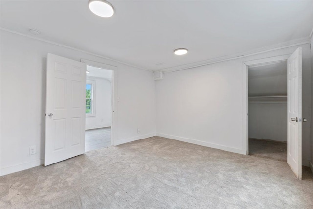 unfurnished bedroom featuring crown molding, a closet, and light colored carpet