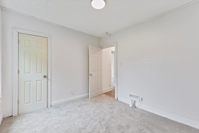 carpeted empty room featuring crown molding