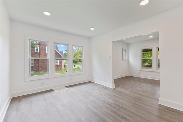 empty room with hardwood / wood-style floors and a healthy amount of sunlight