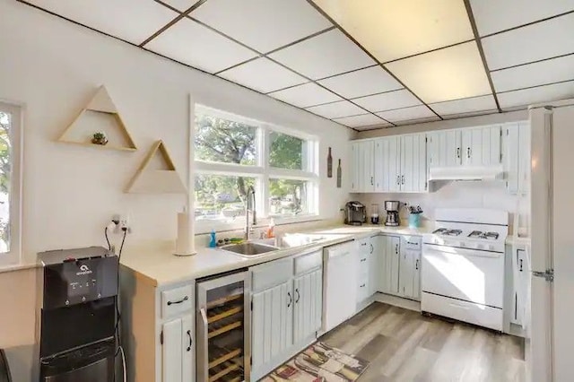 kitchen featuring white cabinetry, a drop ceiling, wine cooler, white appliances, and light wood-type flooring