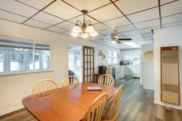 dining space featuring sink, ceiling fan with notable chandelier, a drop ceiling, and dark hardwood / wood-style floors