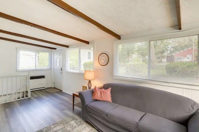 living room with radiator, a textured ceiling, beam ceiling, wood-type flooring, and heating unit