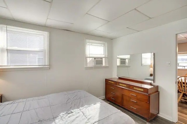 bedroom featuring cooling unit, dark hardwood / wood-style flooring, and multiple windows