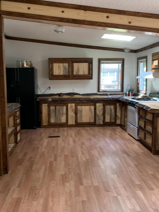 15070 Rapids Dr, Hersey, MI 49639 - kitchen featuring gas range, black fridge with ice dispenser, light wood finished floors, beamed ceiling, and dark countertops