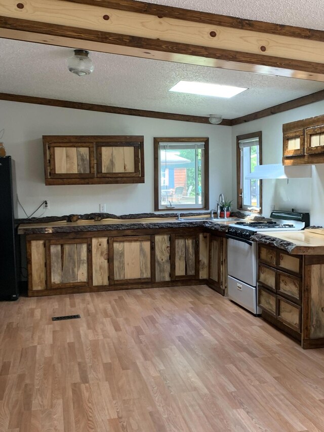 15070 Rapids Dr, Hersey, MI 49639 - kitchen featuring white gas range, freestanding refrigerator, light wood-style flooring, a textured ceiling, and beam ceiling