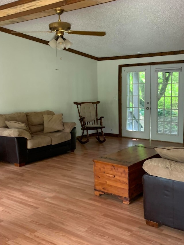 living room with beam ceiling, ceiling fan, french doors, hardwood / wood-style floors, and a textured ceiling