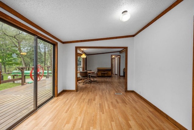 interior space featuring vaulted ceiling, ornamental molding, a textured ceiling, and light hardwood / wood-style flooring