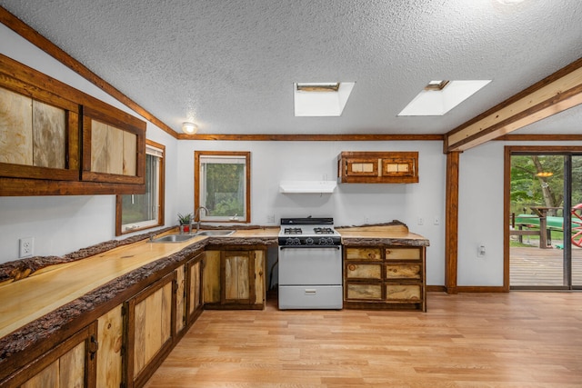 kitchen with a healthy amount of sunlight, a skylight, white gas stove, and light hardwood / wood-style floors