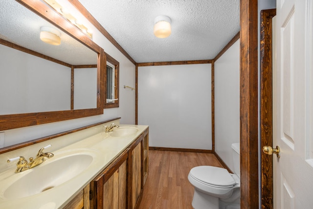 bathroom with vanity, a textured ceiling, crown molding, hardwood / wood-style flooring, and toilet