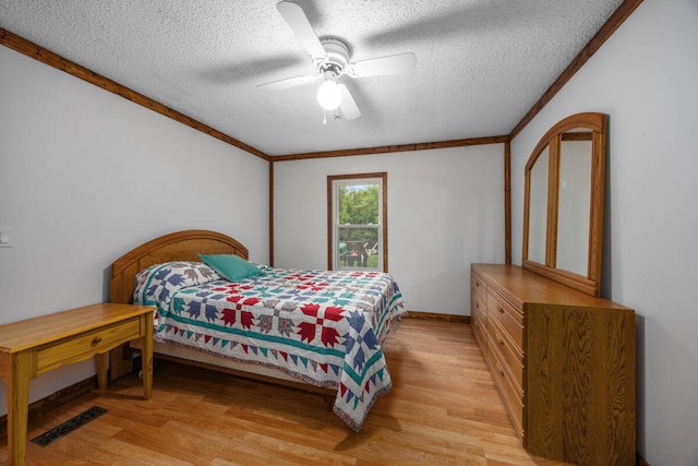 bedroom featuring ceiling fan, crown molding, light hardwood / wood-style floors, and a textured ceiling