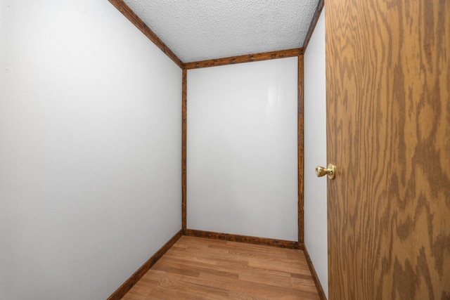 unfurnished room with light hardwood / wood-style floors, a textured ceiling, and ornamental molding