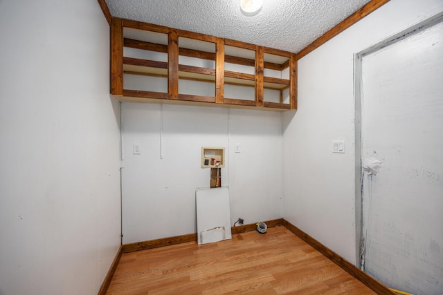 clothes washing area with hookup for a washing machine, light hardwood / wood-style flooring, and a textured ceiling