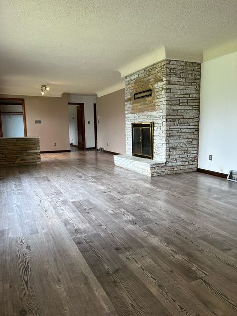 unfurnished living room featuring a textured ceiling, dark hardwood / wood-style flooring, and a fireplace