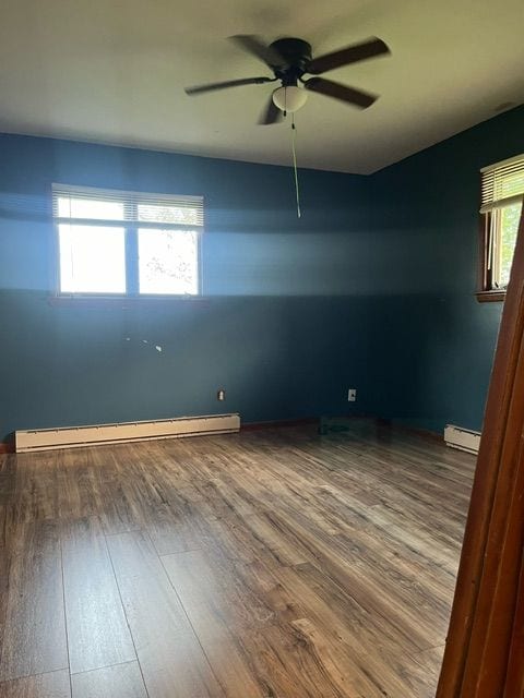 spare room with hardwood / wood-style flooring, ceiling fan, and a baseboard heating unit