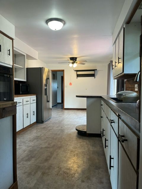 kitchen with black appliances, ceiling fan, and white cabinets