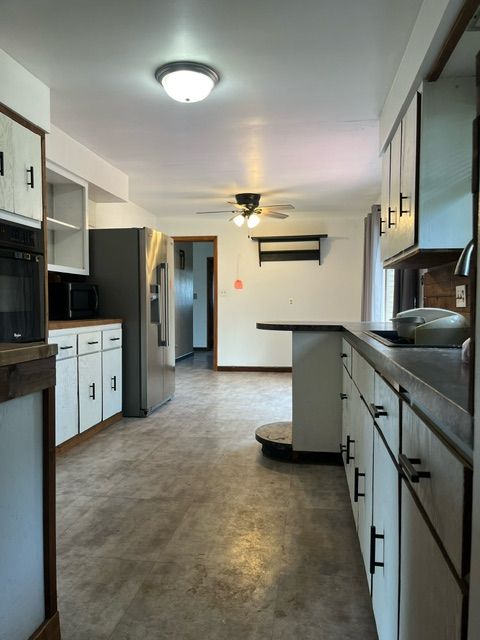 1131 W Sanilac Rd, Sandusky, MI 48471 - kitchen with black appliances, a ceiling fan, white cabinets, concrete floors, and dark countertops