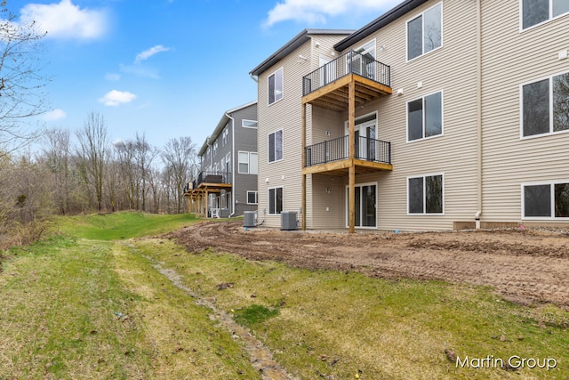 rear view of property featuring a lawn and central AC