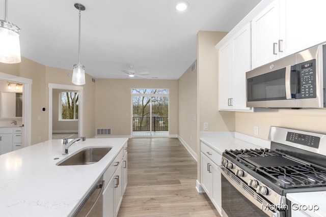 kitchen with appliances with stainless steel finishes, white cabinetry, pendant lighting, and sink