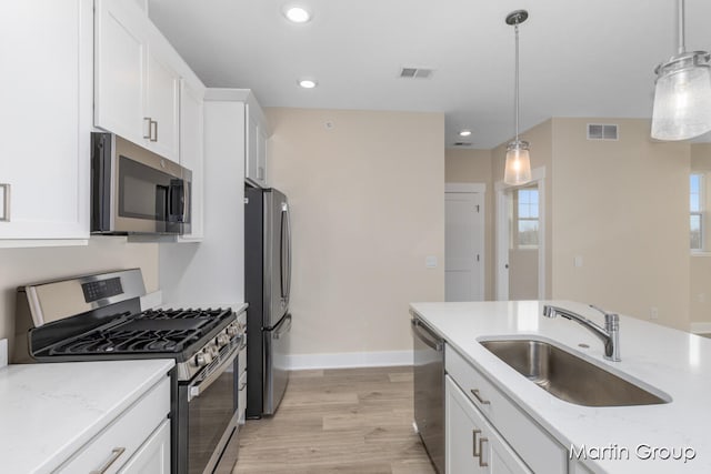 kitchen with hanging light fixtures, white cabinetry, sink, and appliances with stainless steel finishes