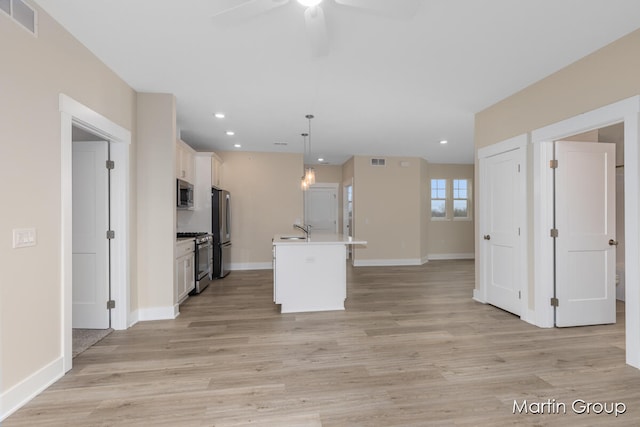 kitchen featuring a center island with sink, decorative light fixtures, light hardwood / wood-style floors, and stainless steel appliances