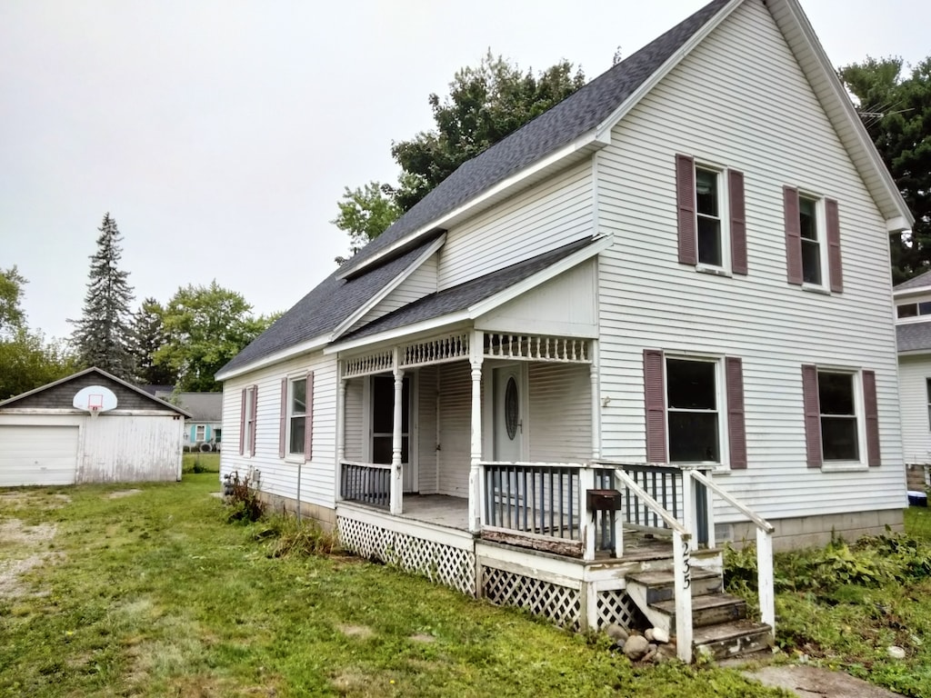 view of front of property with an outbuilding, a front lawn, a porch, and a garage