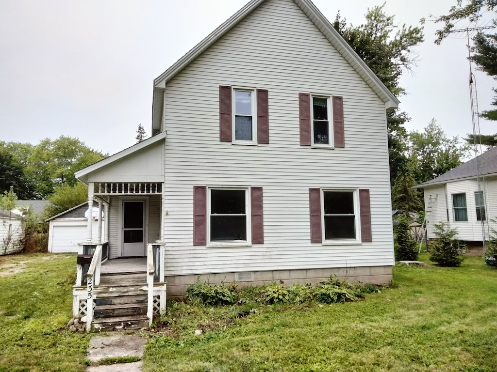 back of house featuring a garage, an outdoor structure, and a lawn