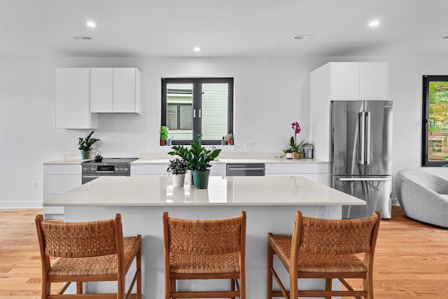 kitchen with white cabinetry, a wealth of natural light, stainless steel appliances, and light wood-type flooring