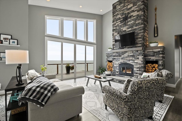 living room with hardwood / wood-style flooring, a towering ceiling, and a fireplace