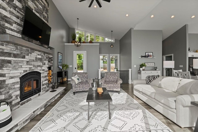 living room with high vaulted ceiling, wood-type flooring, and ceiling fan with notable chandelier