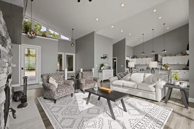 living room featuring a notable chandelier, light wood-type flooring, and high vaulted ceiling