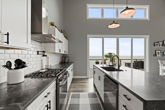 kitchen featuring white cabinets, dishwasher, stainless steel stove, and wall chimney range hood