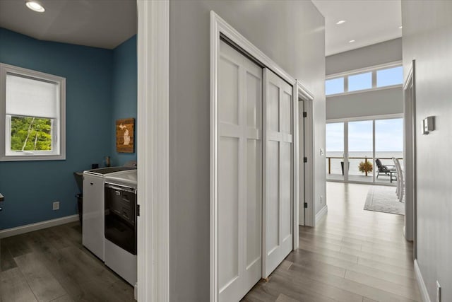 corridor featuring a wealth of natural light, washer and dryer, and dark wood-type flooring