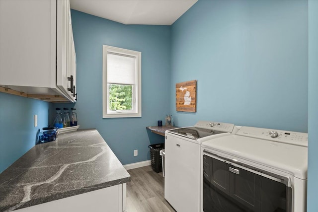 washroom with cabinets, washing machine and dryer, and light hardwood / wood-style flooring