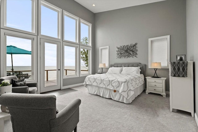 bedroom featuring access to exterior, light carpet, and a towering ceiling