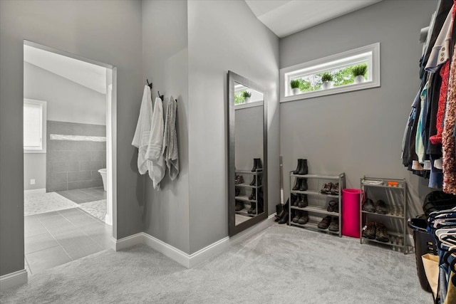 bathroom with tile patterned flooring, vaulted ceiling, and walk in shower