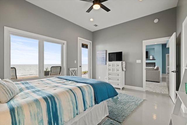 bedroom featuring ceiling fan, a water view, and a fireplace