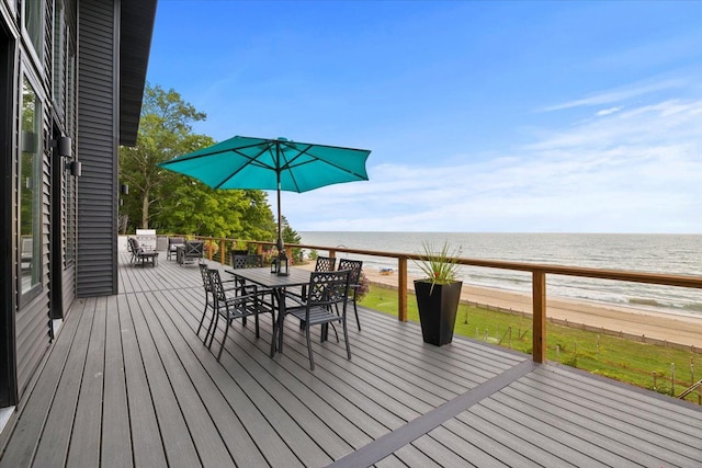 wooden deck featuring a beach view and a water view