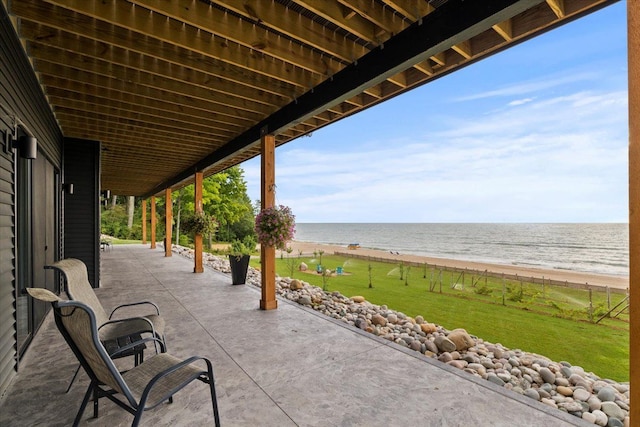 view of patio / terrace with a water view and a beach view